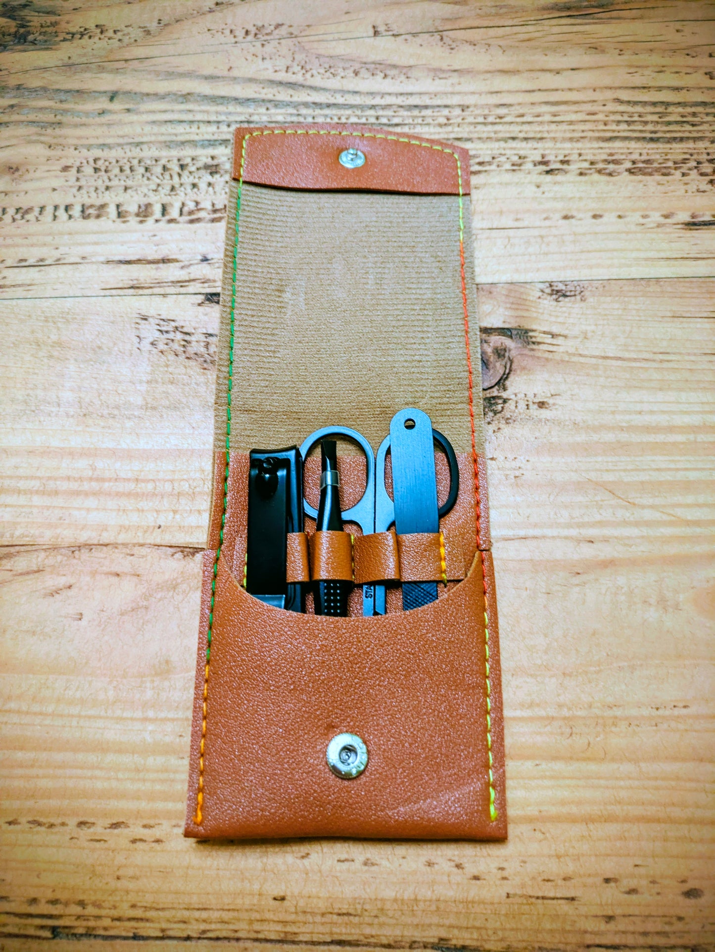 Open view of personalised leather grooming kit for travel, showing neatly arranged manicure tools in stitched compartments.