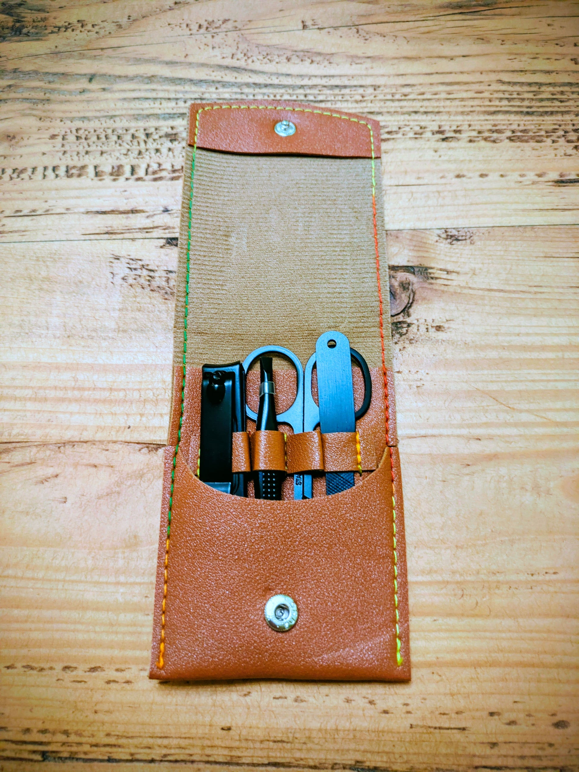 Open view of personalised leather grooming kit for travel, showing neatly arranged manicure tools in stitched compartments.