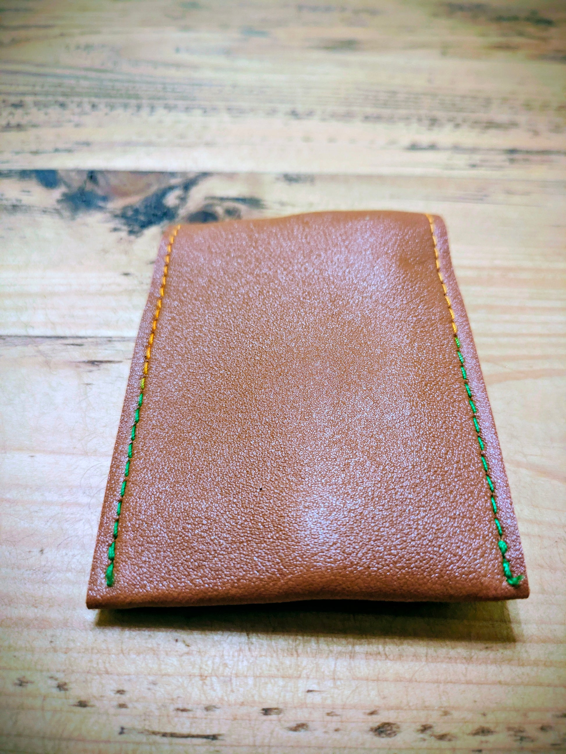 Back view of compact brown leather grooming kit pouch with green and yellow stitching, ready for custom engraving.